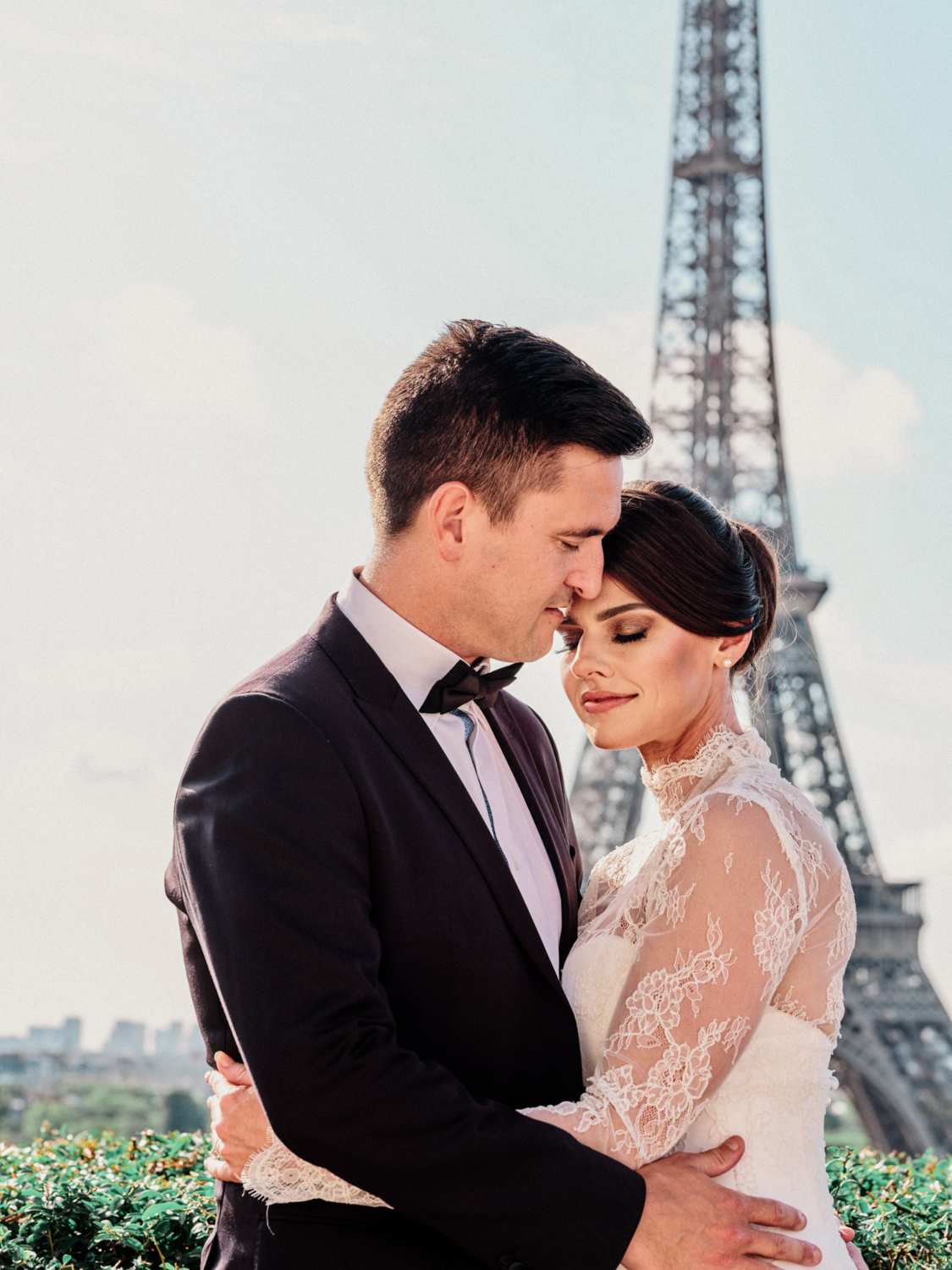 bride and groom embrace with view of eiffel tower in paris