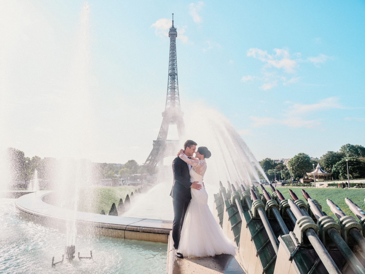 bride and groom embrace with fountains surrounding them