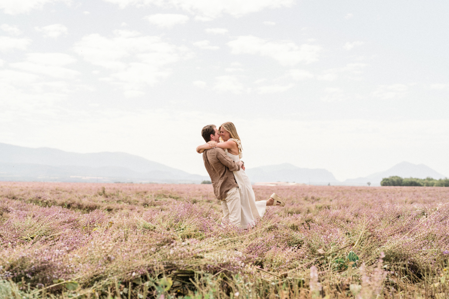 man holds woman in field of pink flowers in provence