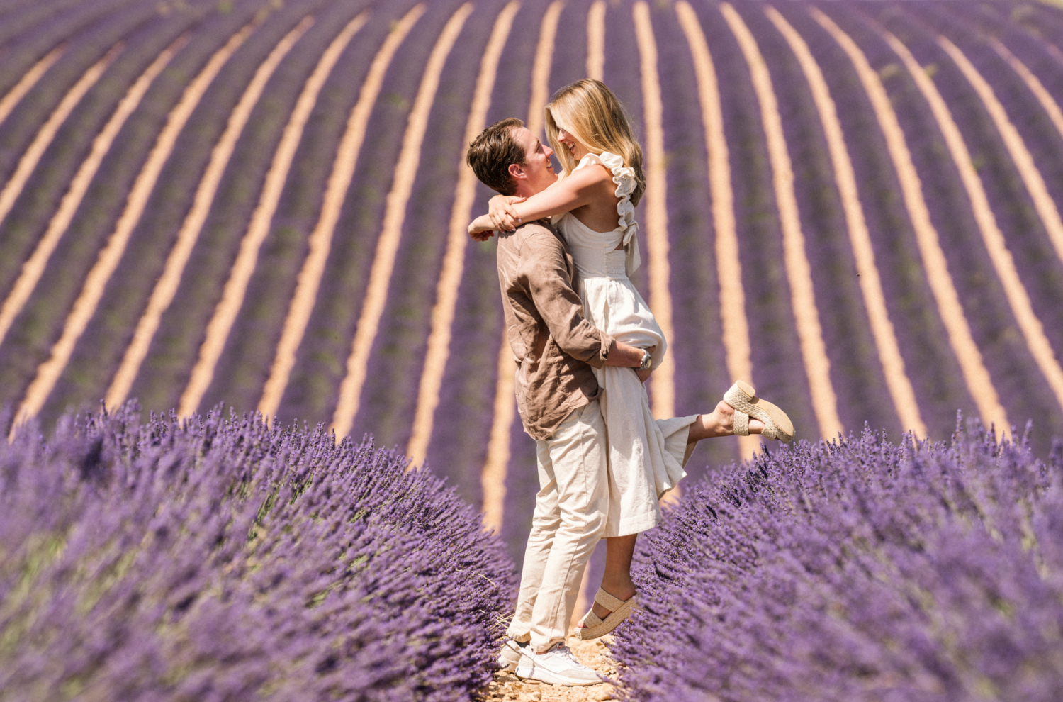 man lifts woman in air in lavender field