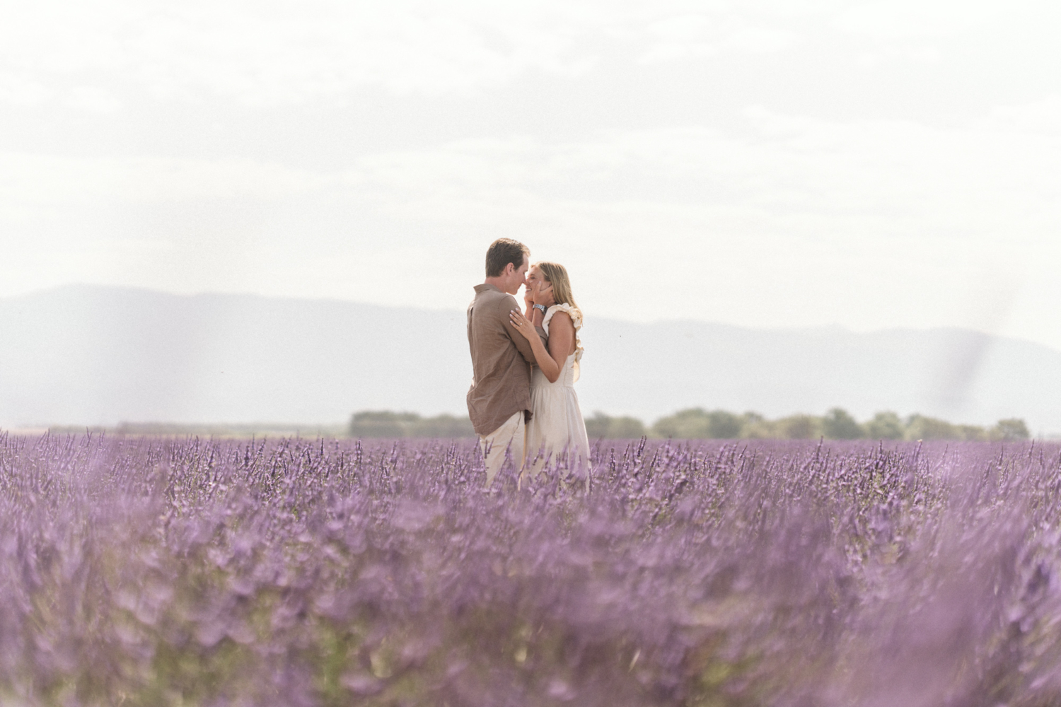 man pulls womans face close in lavender field
