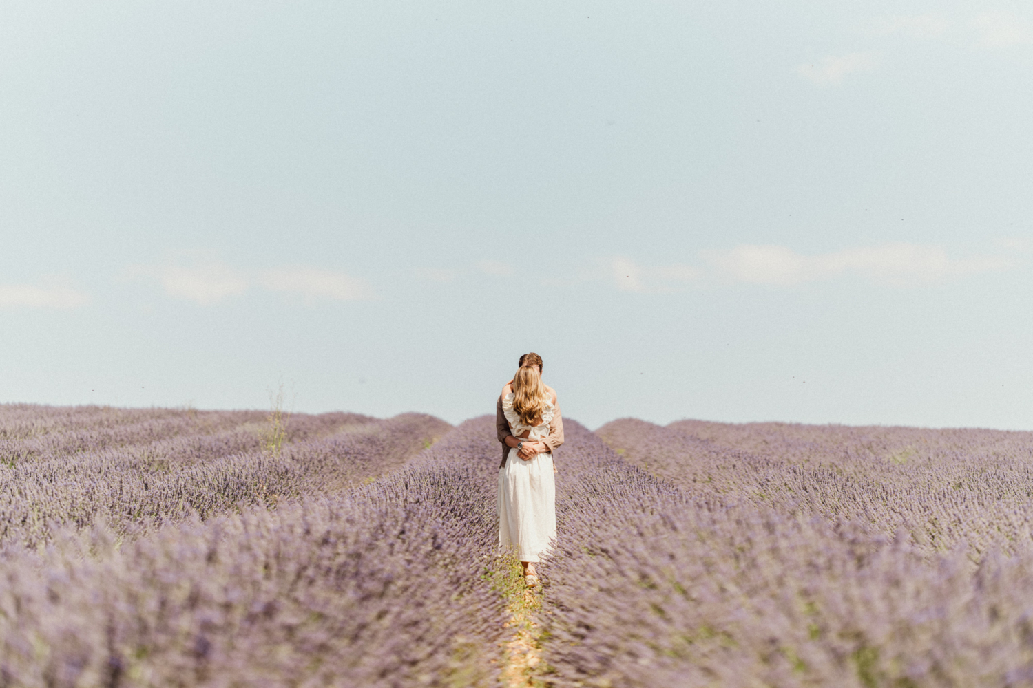 couple embrace in lavender field with blue sky