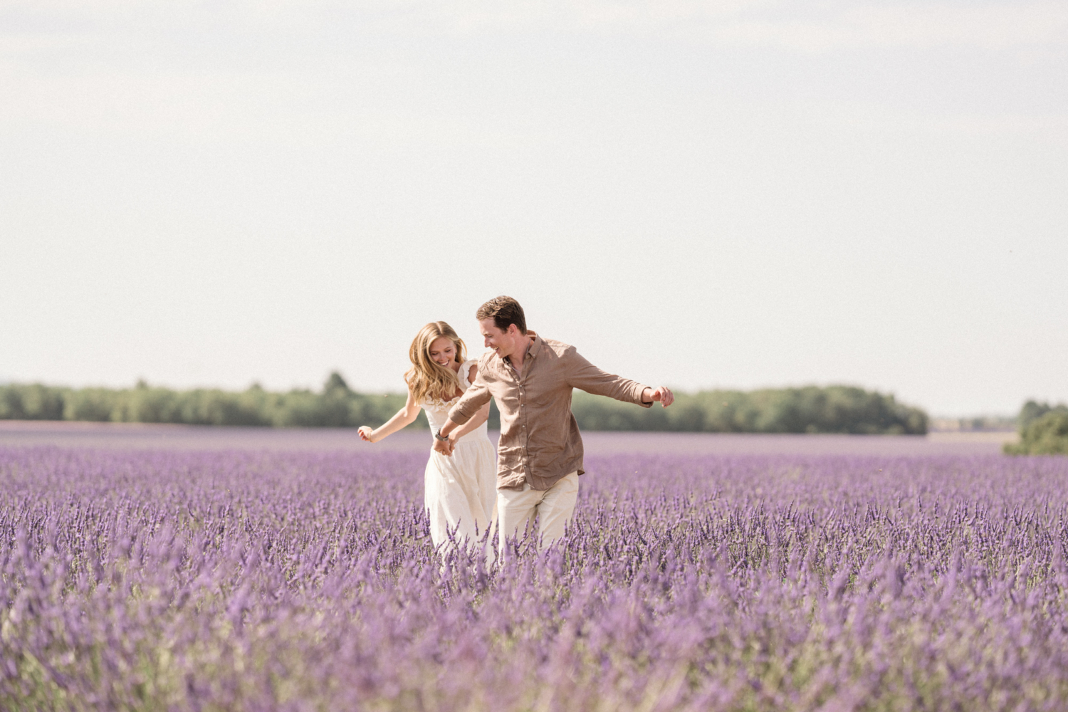 engaged couple run in a lavender field