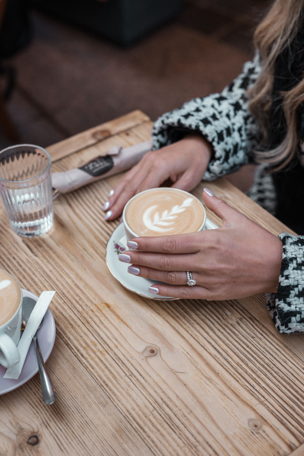 woman holds decorative cup of coffee wearing engagement ring