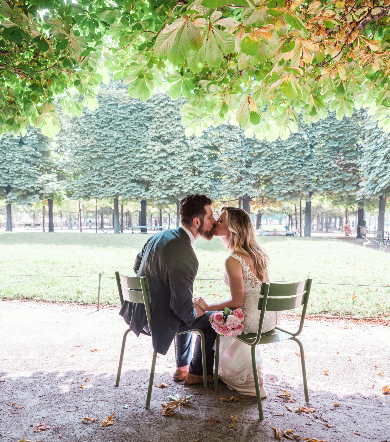 bride and groom sitting on chairs kiss in garden