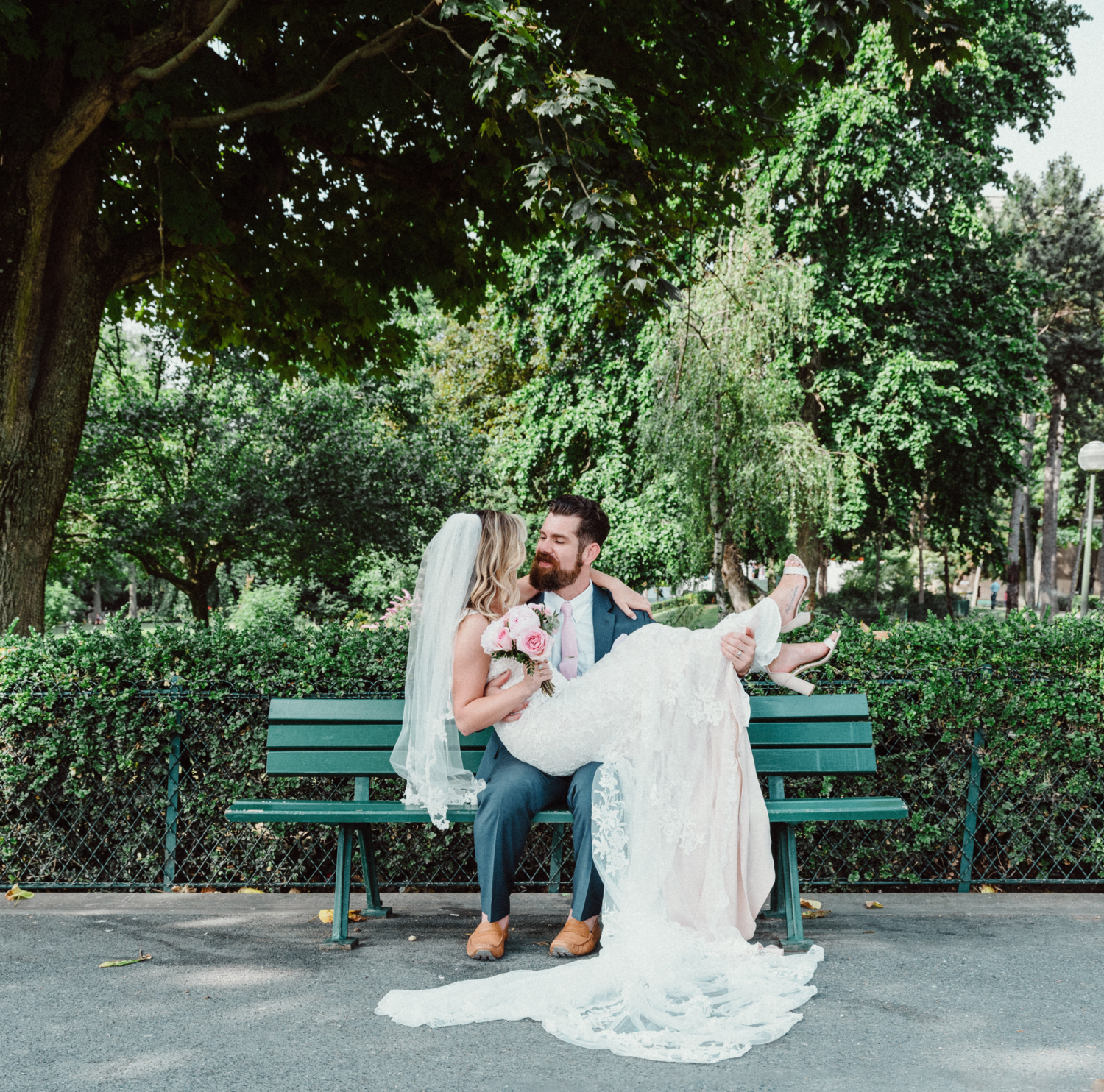 bride and groom sit on bench after wedding in paris france