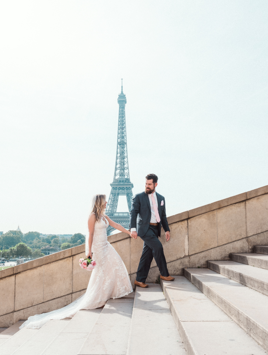 bride and groom climb stairs with view of eiffel tower