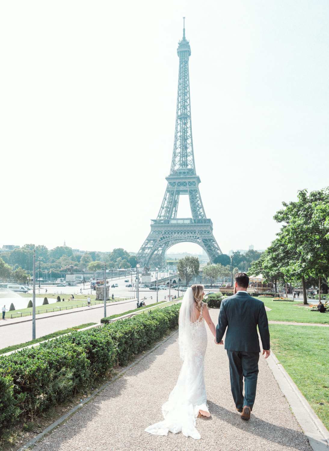 bride and groom walk toward the eiffel tower