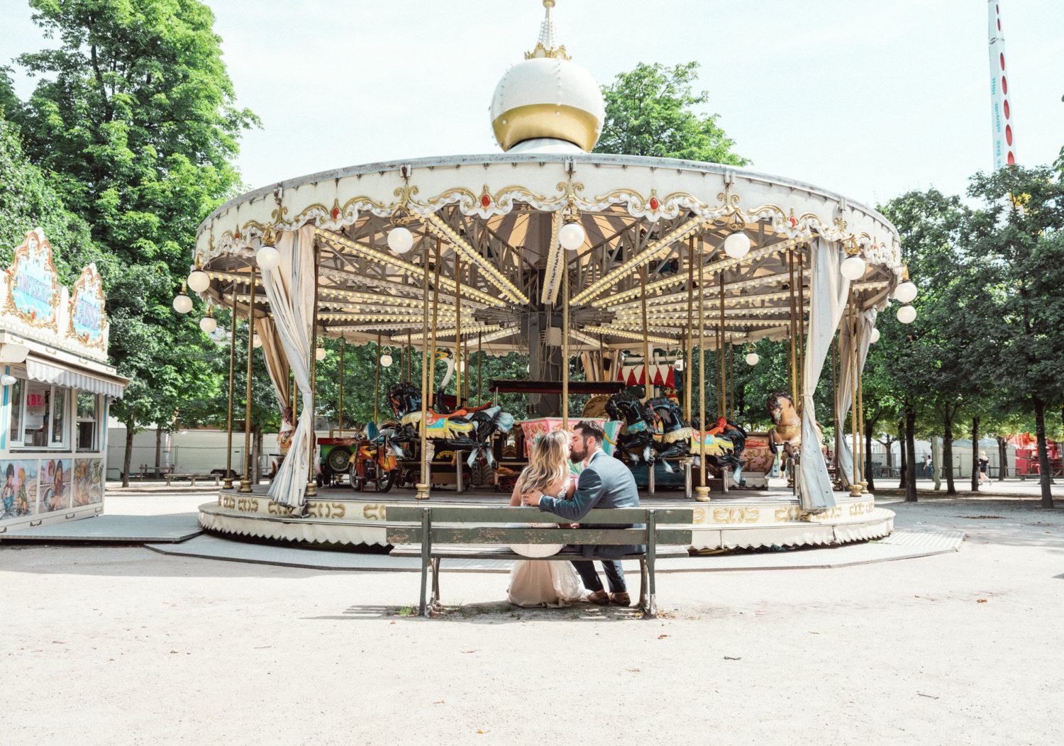 bride and groom kiss next to carousel in paris france