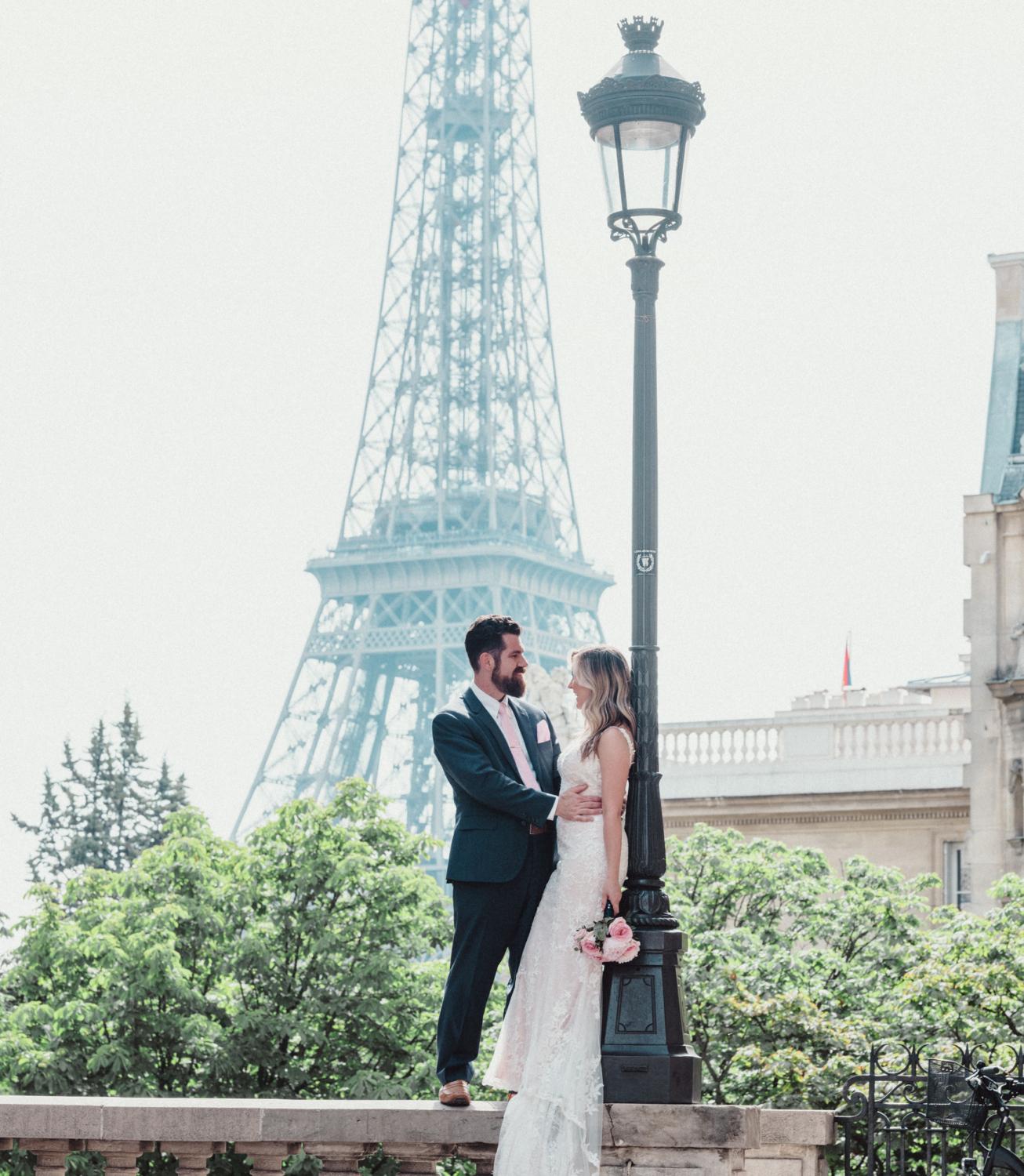 bride and groom laugh with a view of the eiffel tower in paris