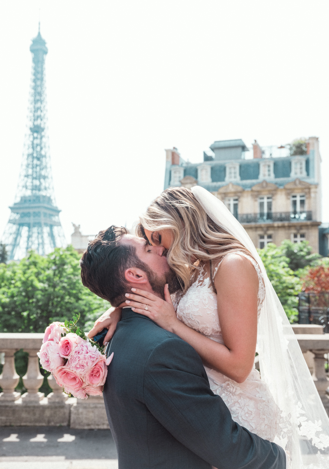 bride and groom kiss passionately with view of eiffel tower