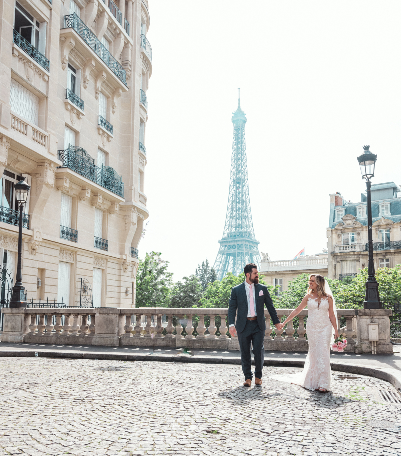 bride and groom walk hand in hand with view of eiffel tower paris
