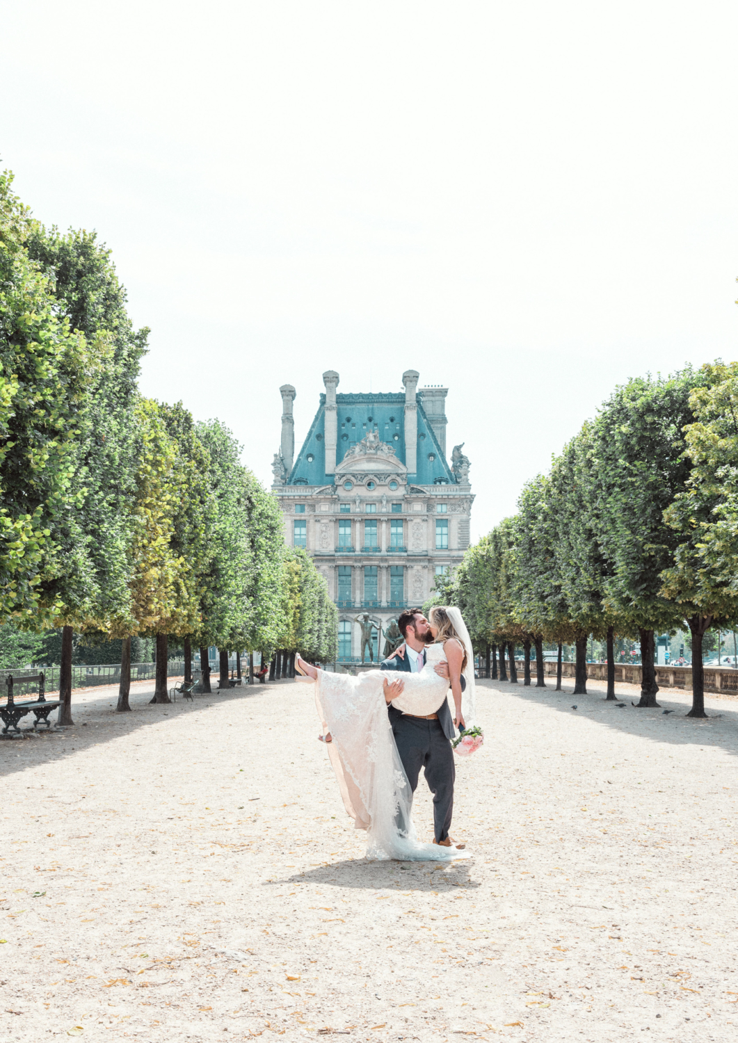 groom carries bride in garden paris france