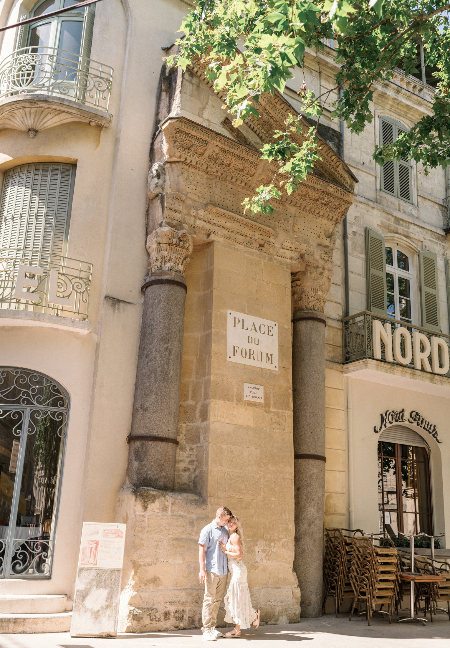 young engaged couple pose in front of place du form in arles france