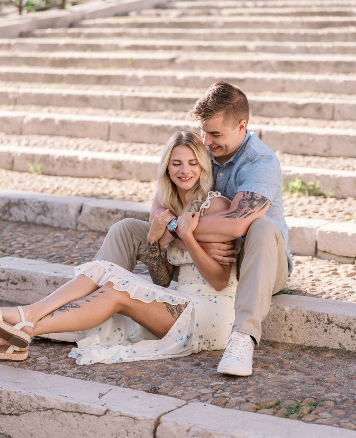 young engaged couple embrace on the stairs of the roman amphitheater in arles france