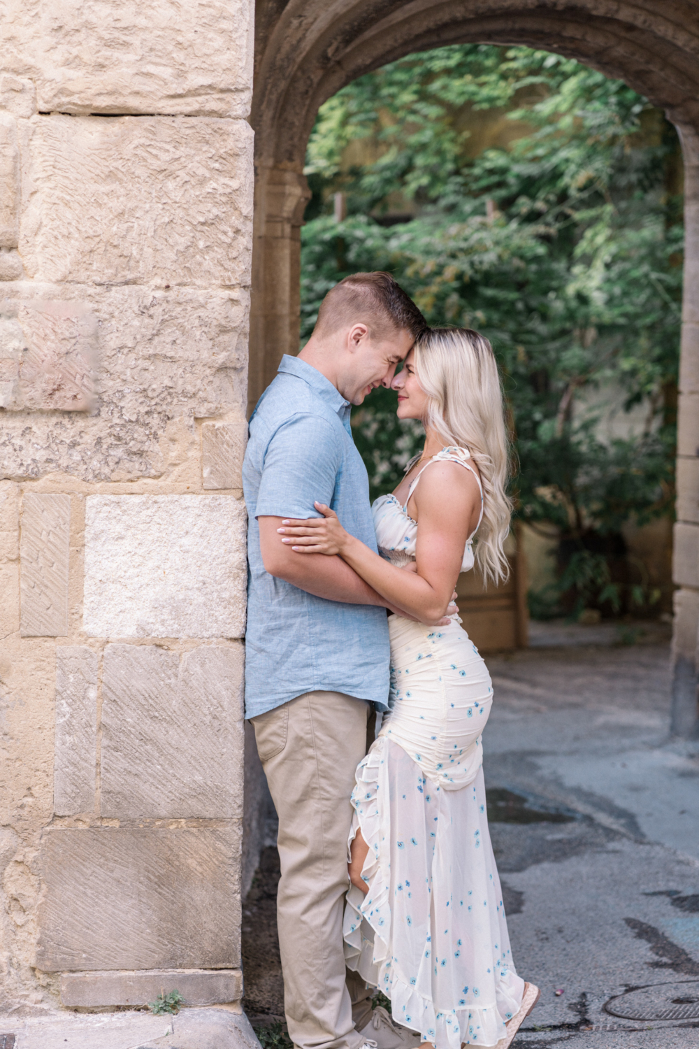 young engaged couple embrace next to stone wall in arles france