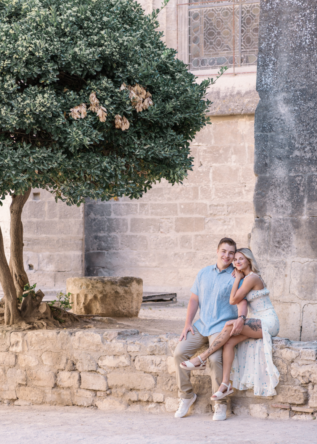 young engaged couple pose next to tree in arles france