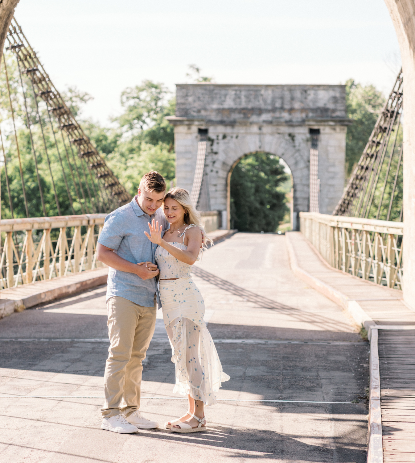 young engaged couple admire engagement ring on bridge