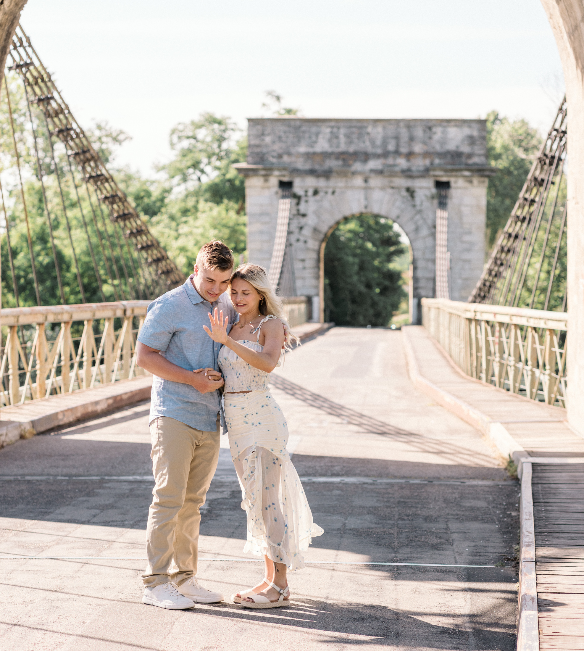 young engaged couple admire engagement ring on bridge during Engagement Photos In Provence