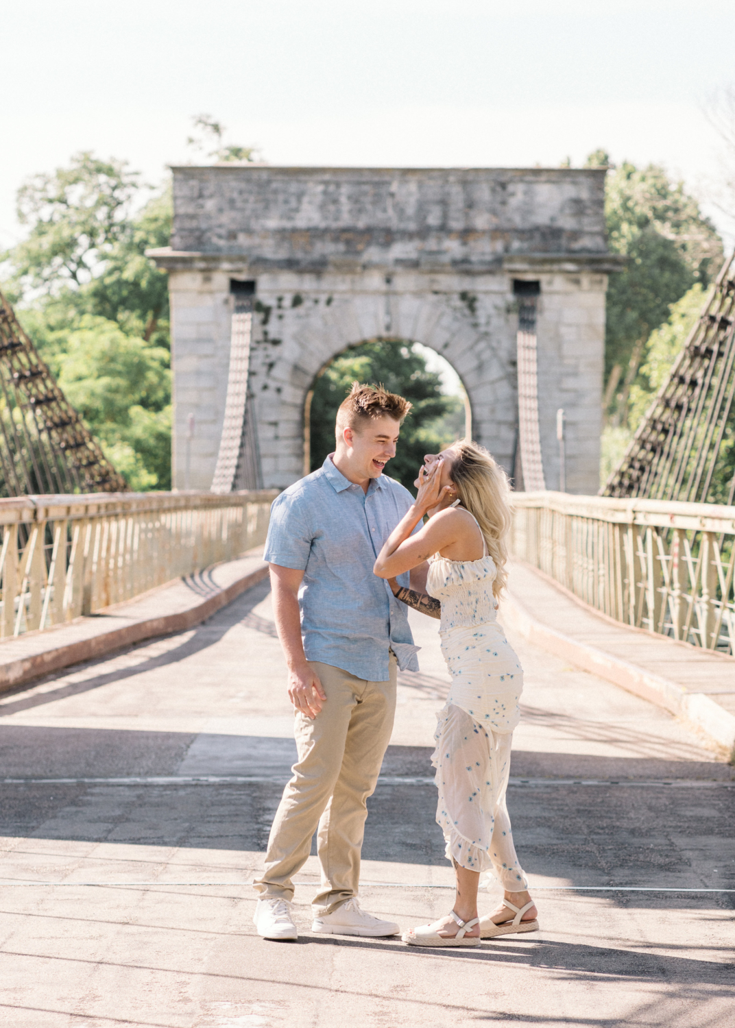 young engaged couple laugh after their engagement on bridge in arles france