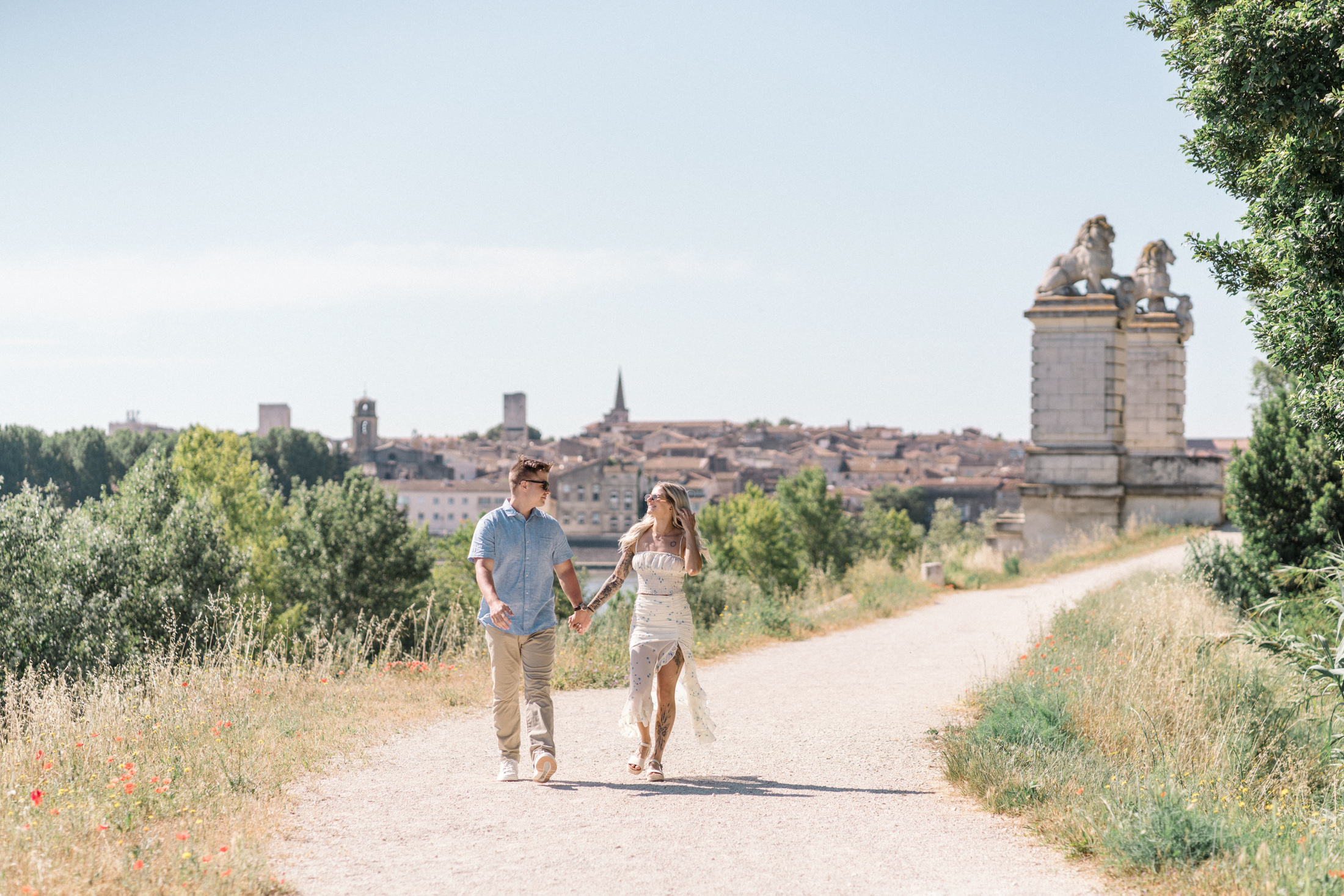 young engaged couple walk hand in hand and laugh in arles france