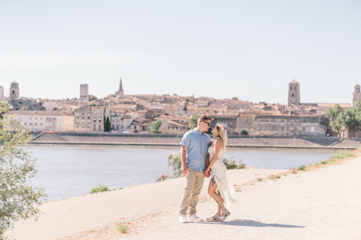 young engaged couple pose with medieval village in background in arles france