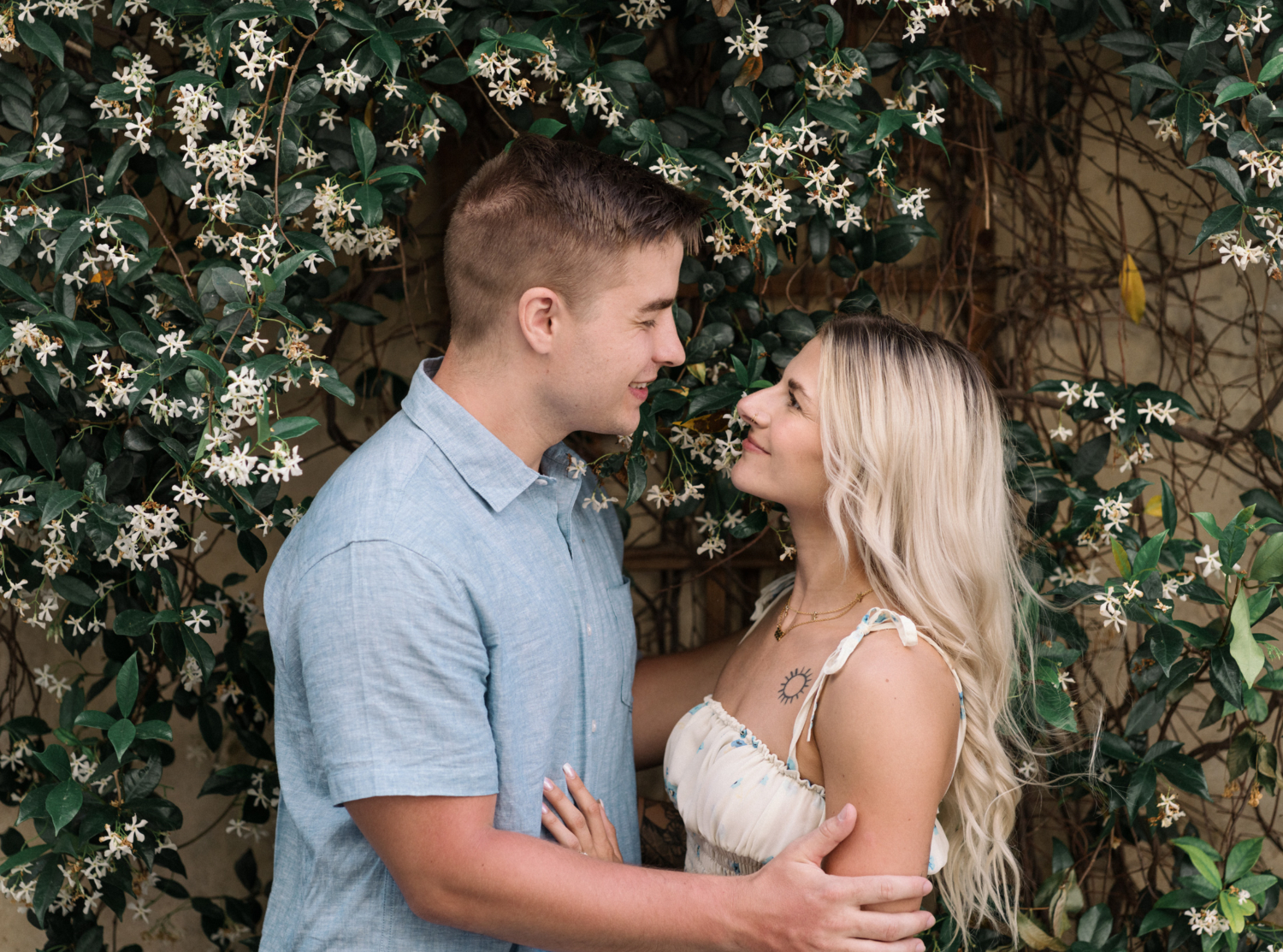 young engaged couple pose in front of jasmine tree in arles france