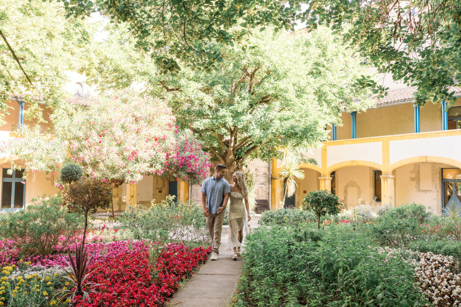 young engaged couple walk in beautiful garden in arles france