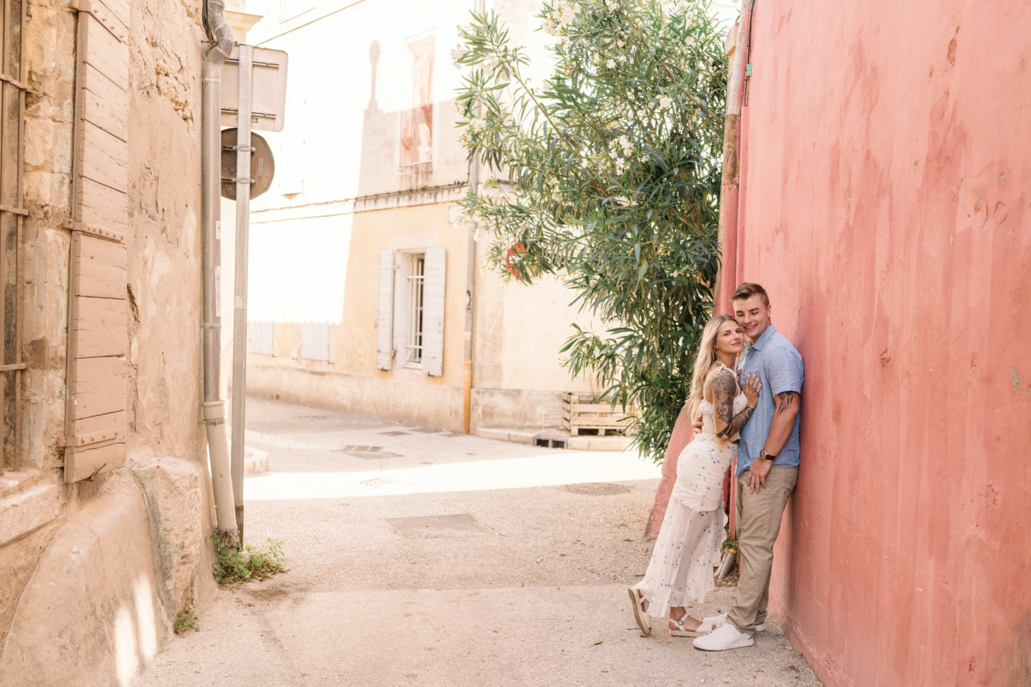 young engaged couple pose next to orange house in arles france