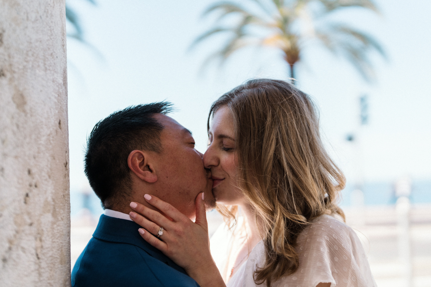 woman kisses man near palm tree in nice, france