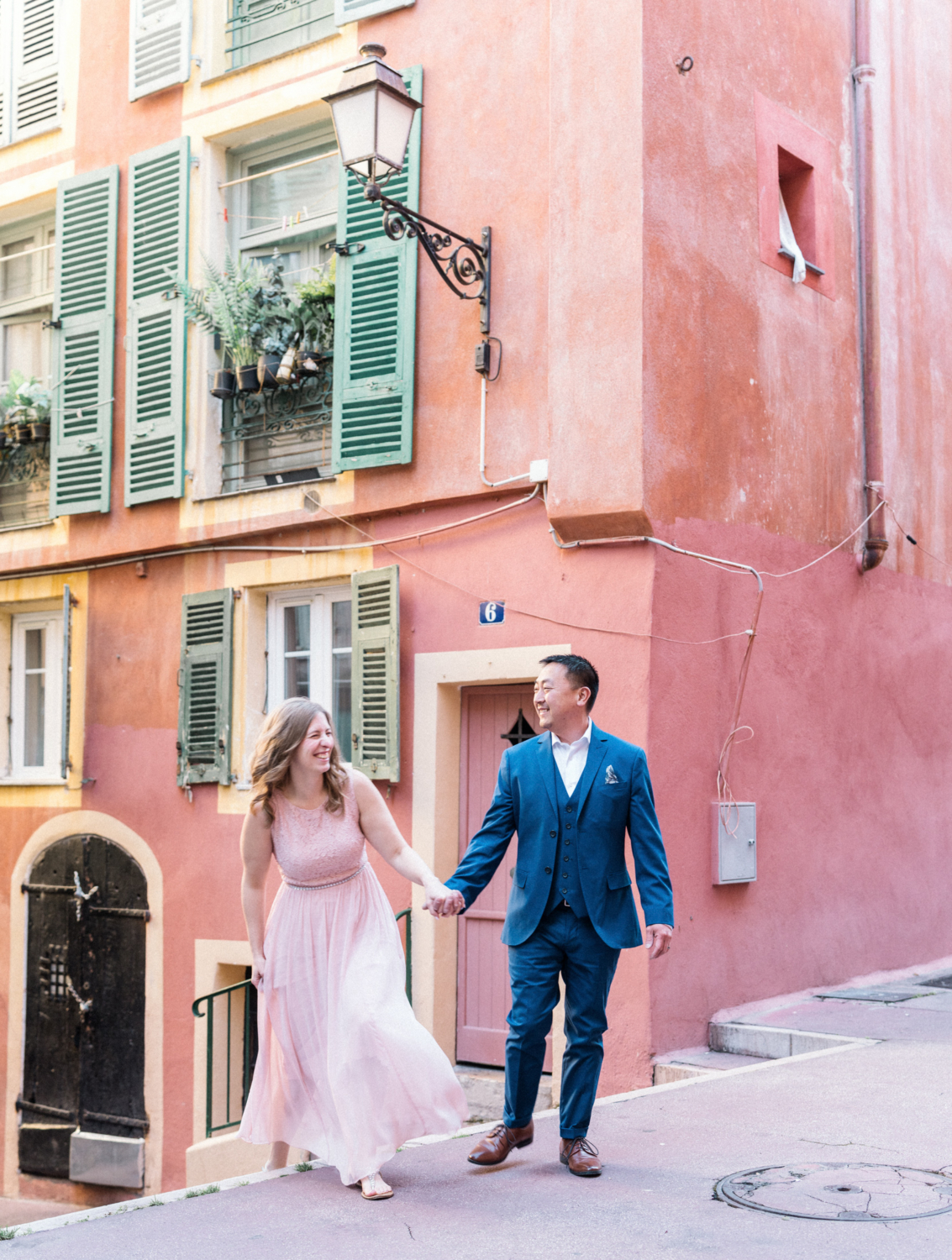 newly engaged couple laugh and walk together in nice, france