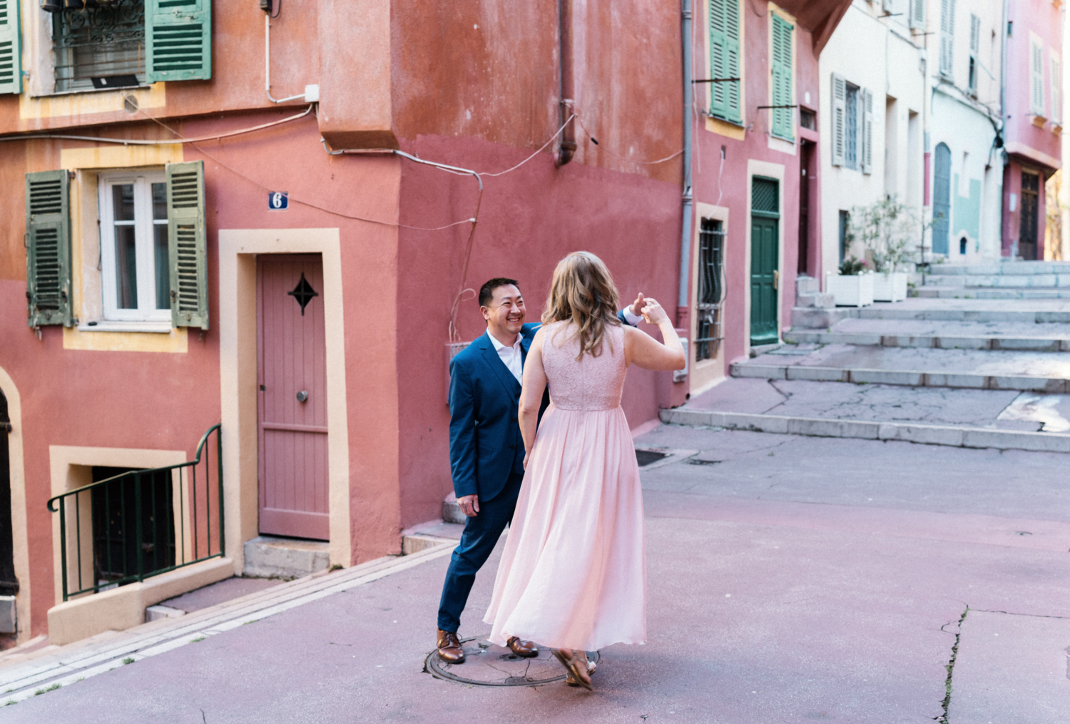 cute couple dance next to colorful buildings in nice, france