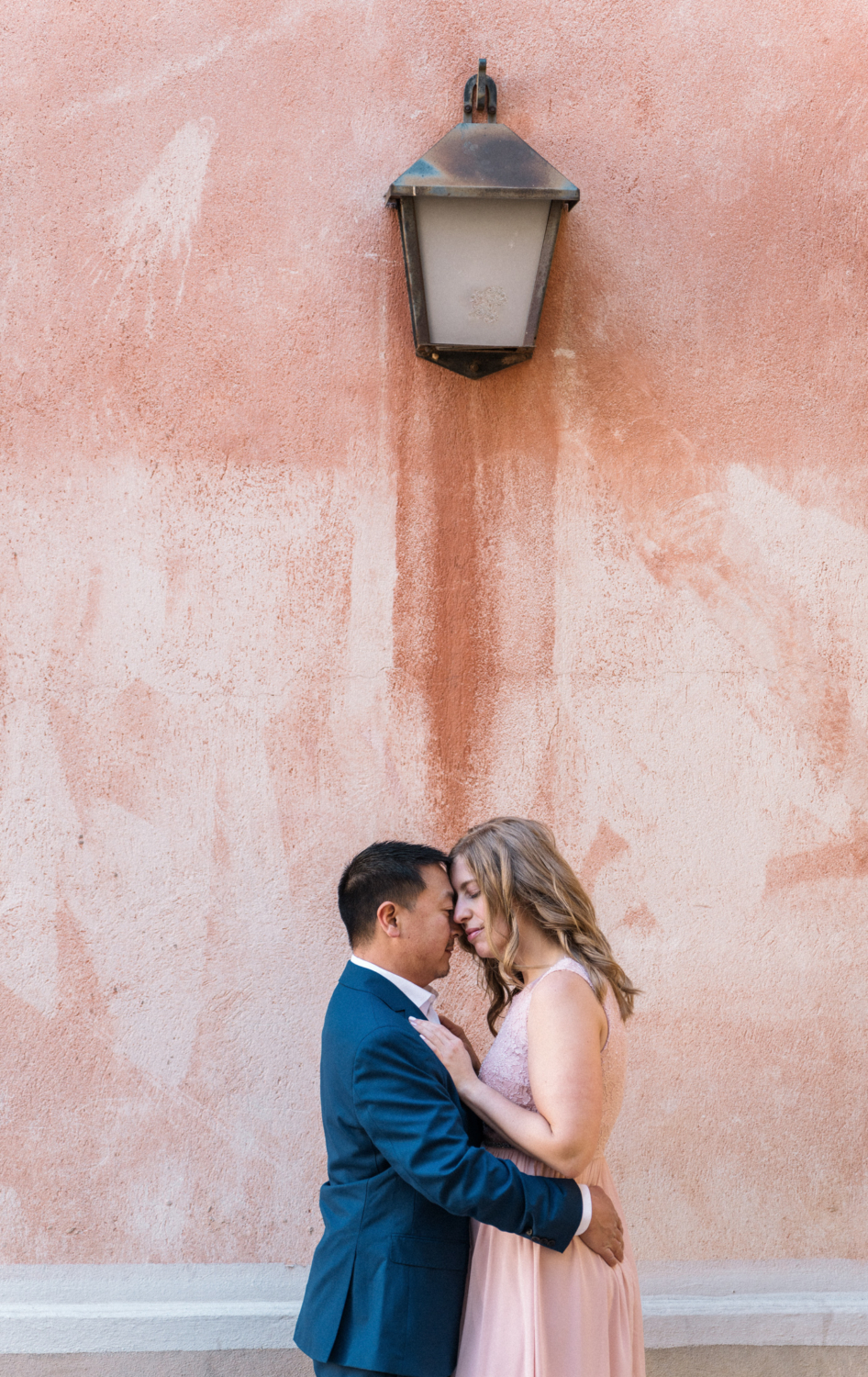 newly engaged couple embrace next to orange wall in nice, france