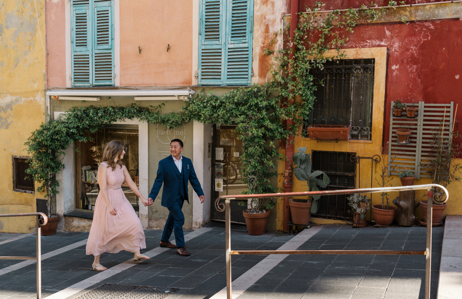 engaged couple walk by colorful building in nice, france