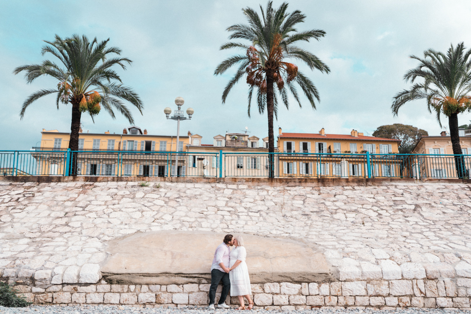 couple share passionate kiss with palm trees in background in in nice france