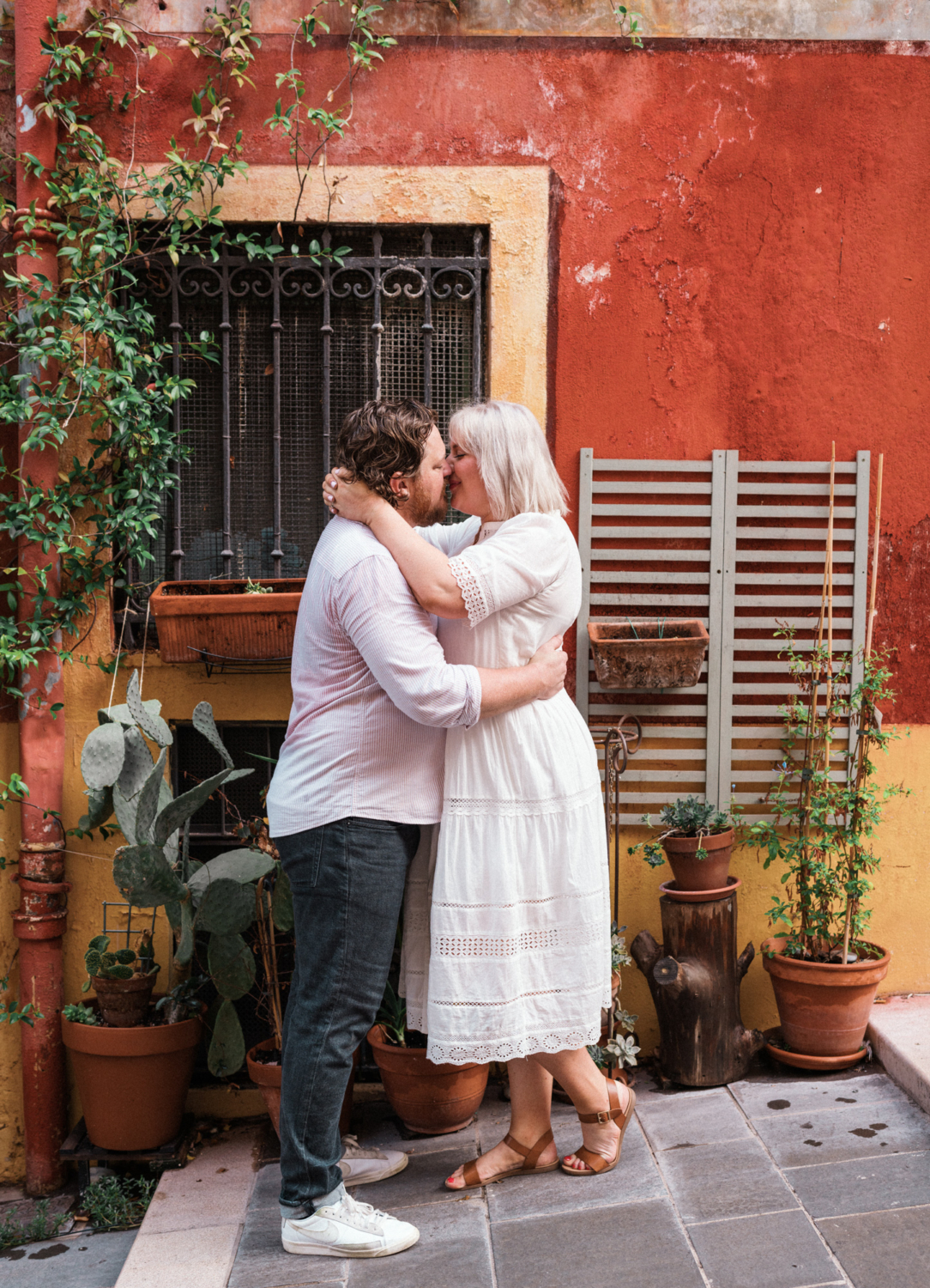 couple share passionate kiss in front of orange building in nice france