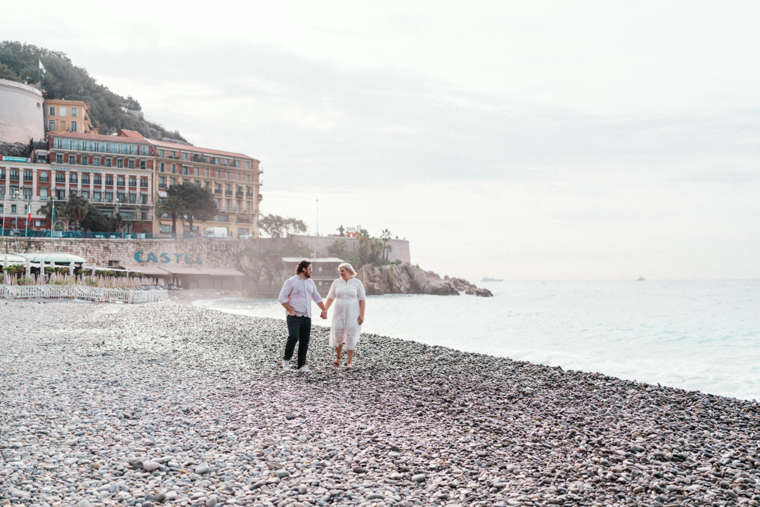 couple walk hand in hand on the beach in nice france