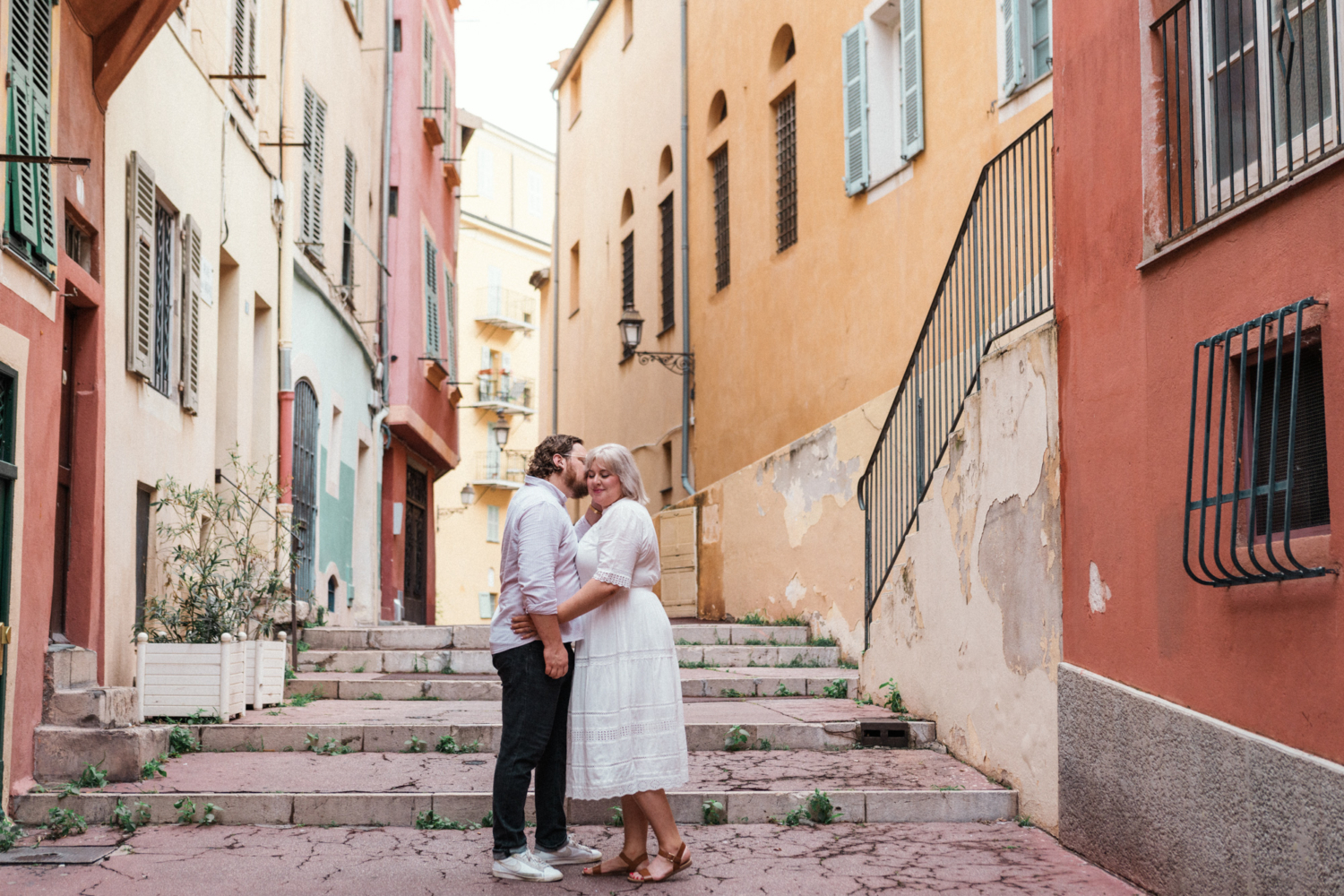 man whispers in womans ear in old town nice france