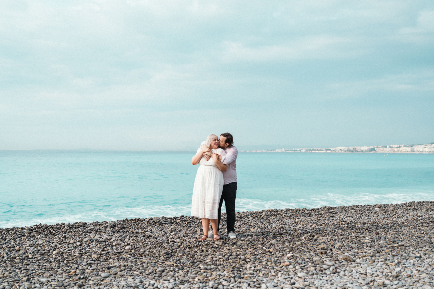 man wraps arms around woman with sea view