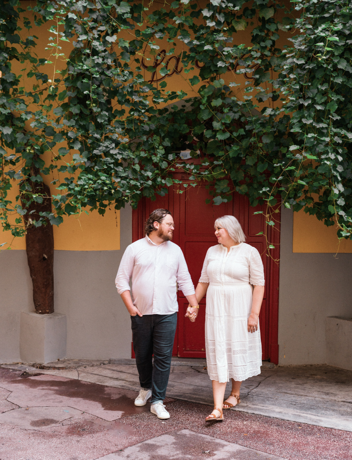 adorable couple walk in front of red door in nice france