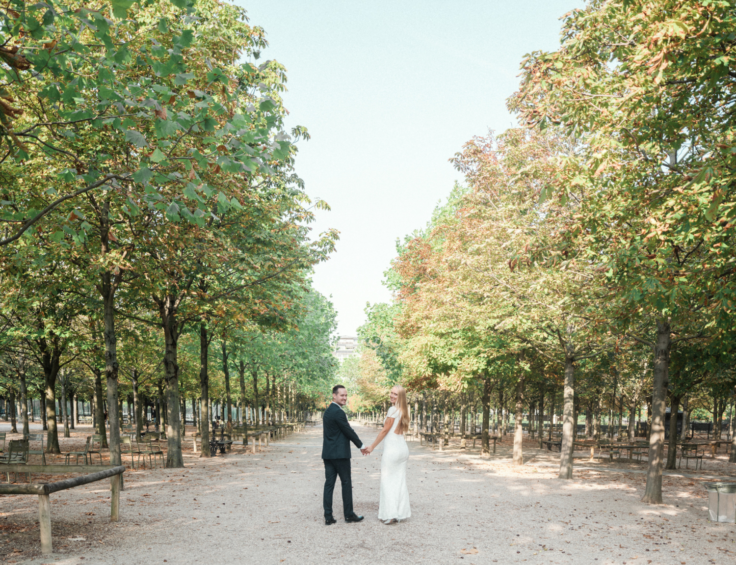 bride and groom smile as they walk through luxembourg gardens paris