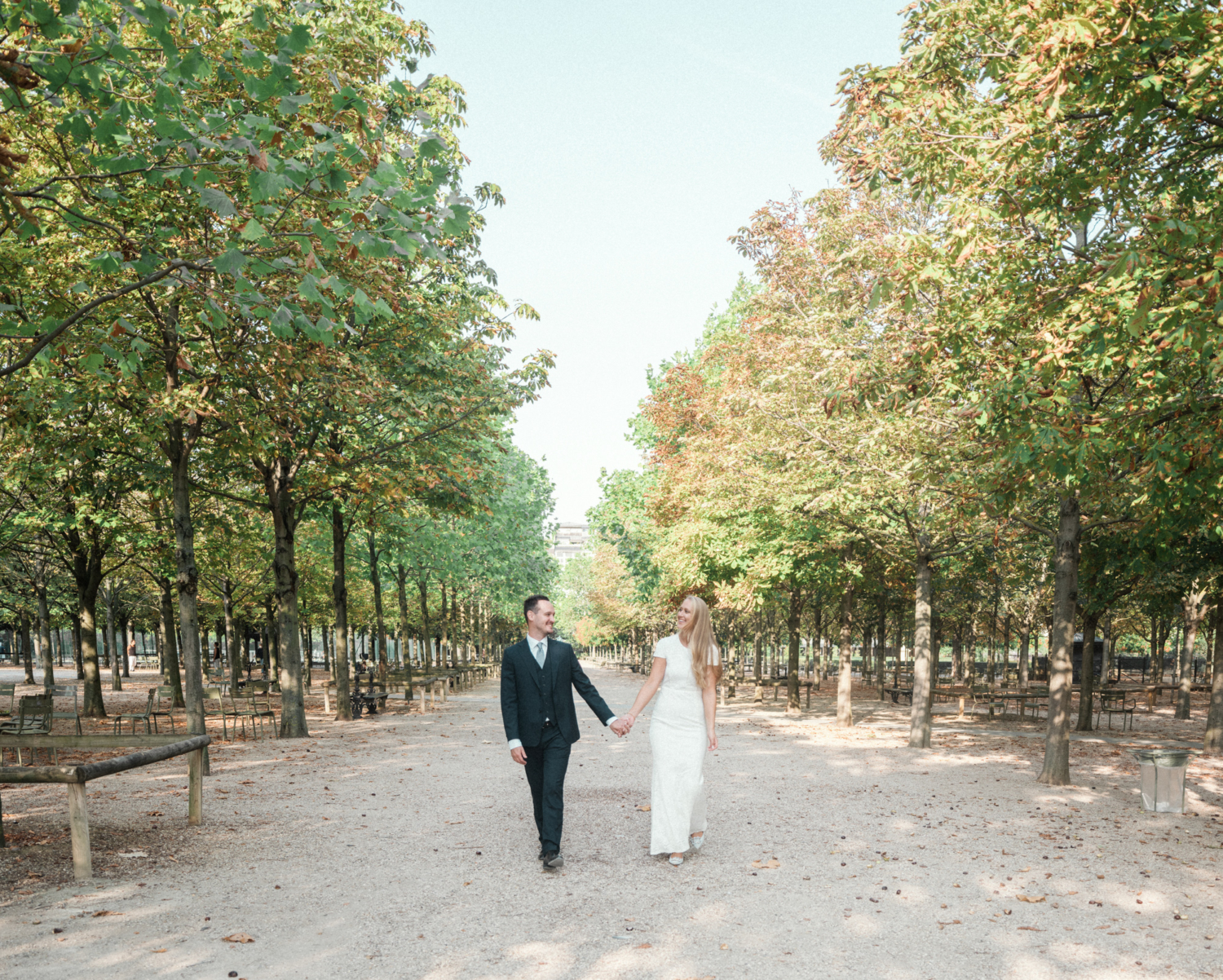 bride and groom laugh and walk through luxembourg gardens