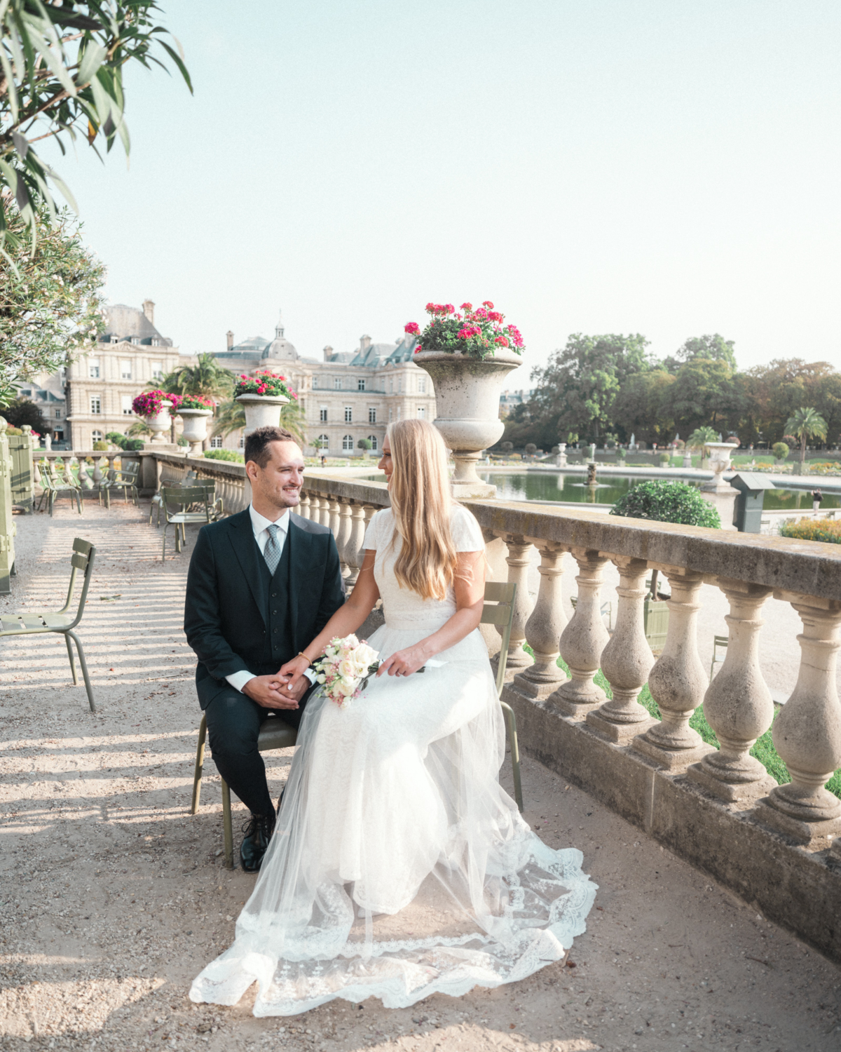 bride and groom sit on chairs at luxembourg gardens paris