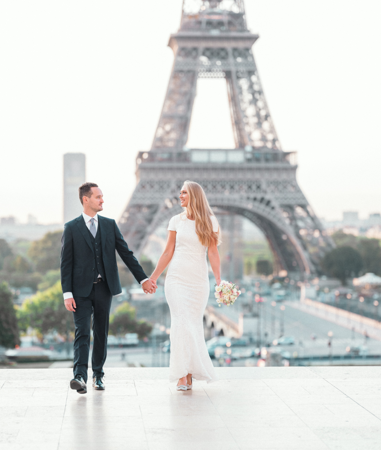 bride and groom walk hand in hand with view of eiffel tower