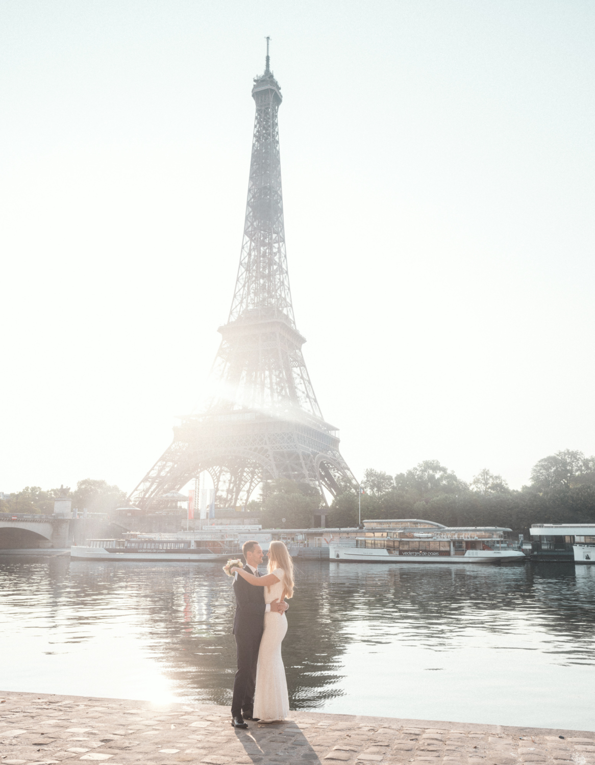 bride and groom embrace at sunrise with view of eiffel tower