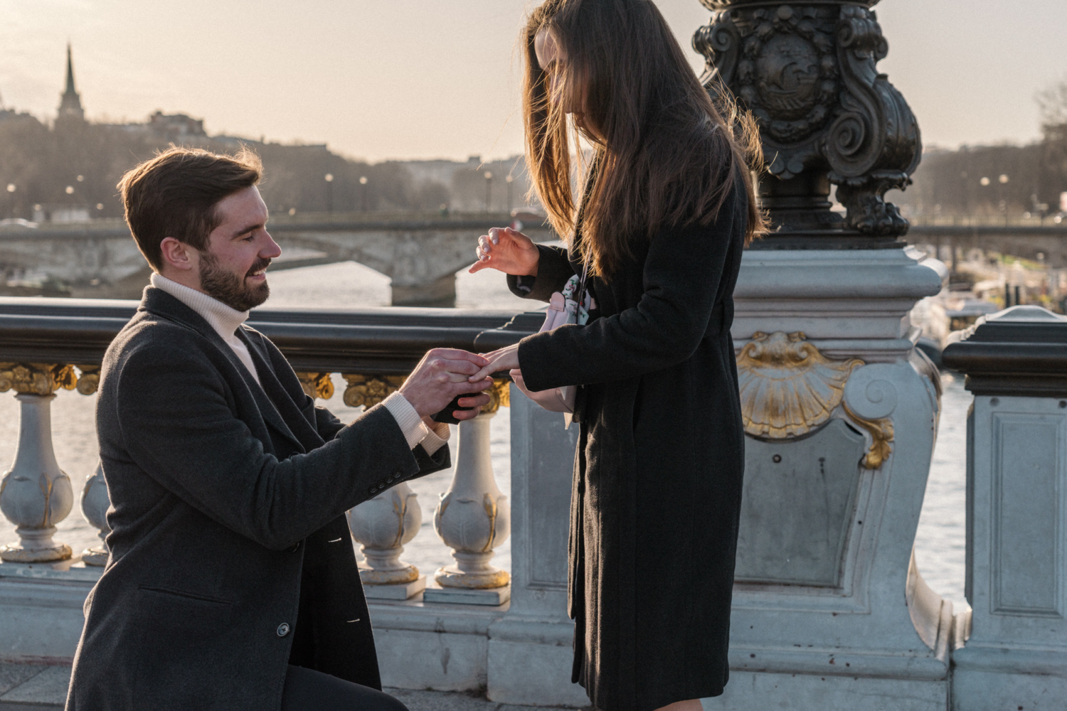 man places ring on woman's finger in paris