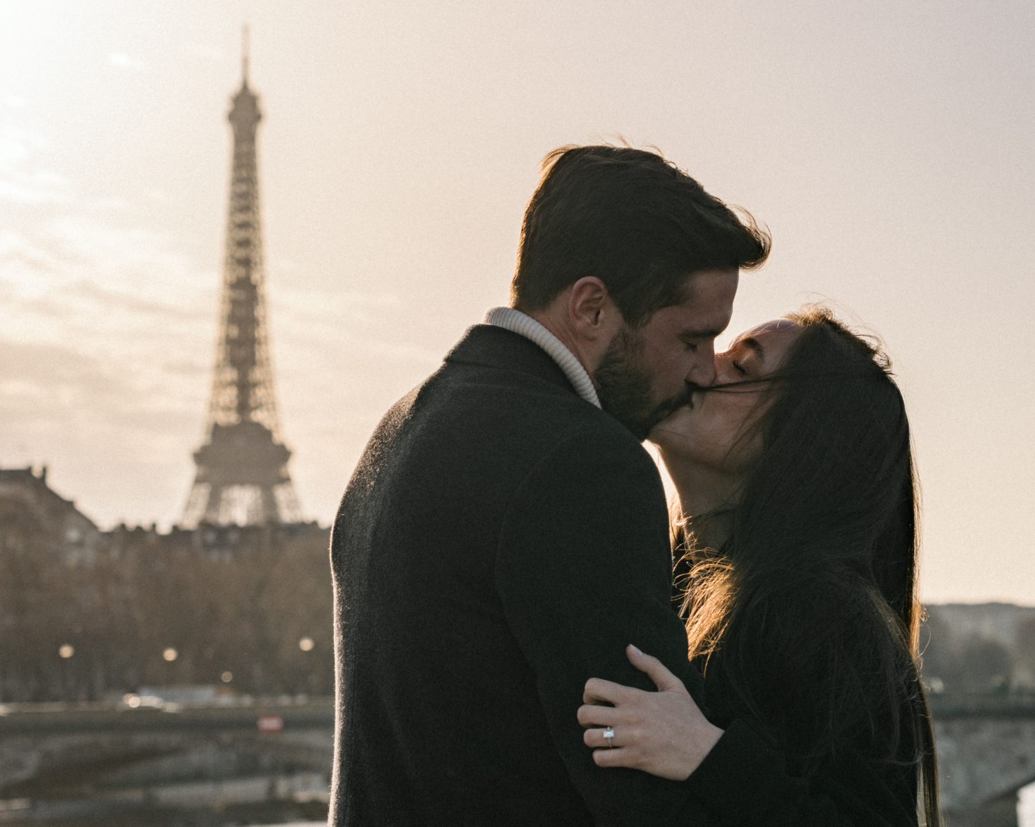 newly engaged couple kiss passionately with view of eiffel tower