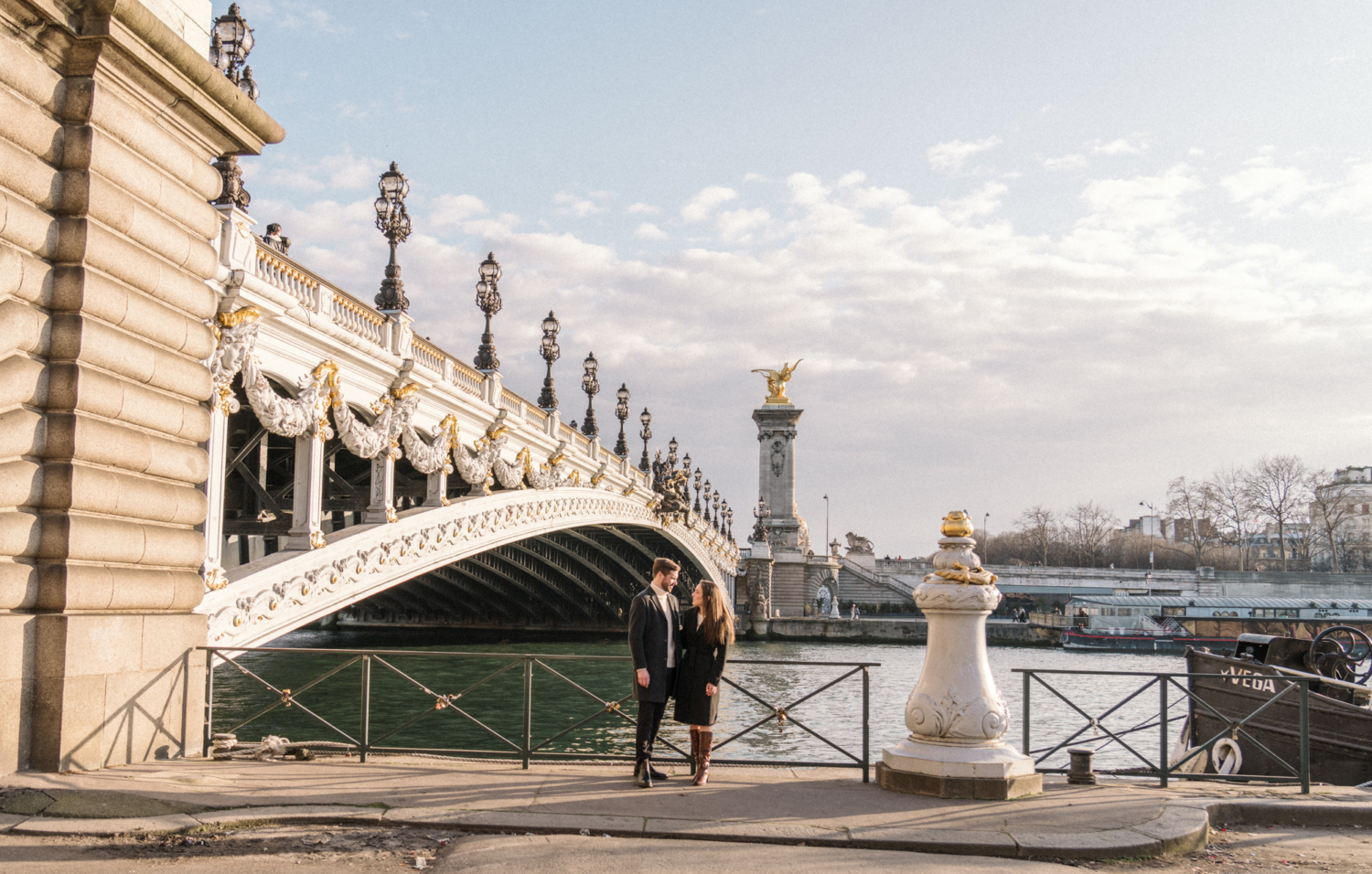newly engaged couple pose under pont alexandre in paris