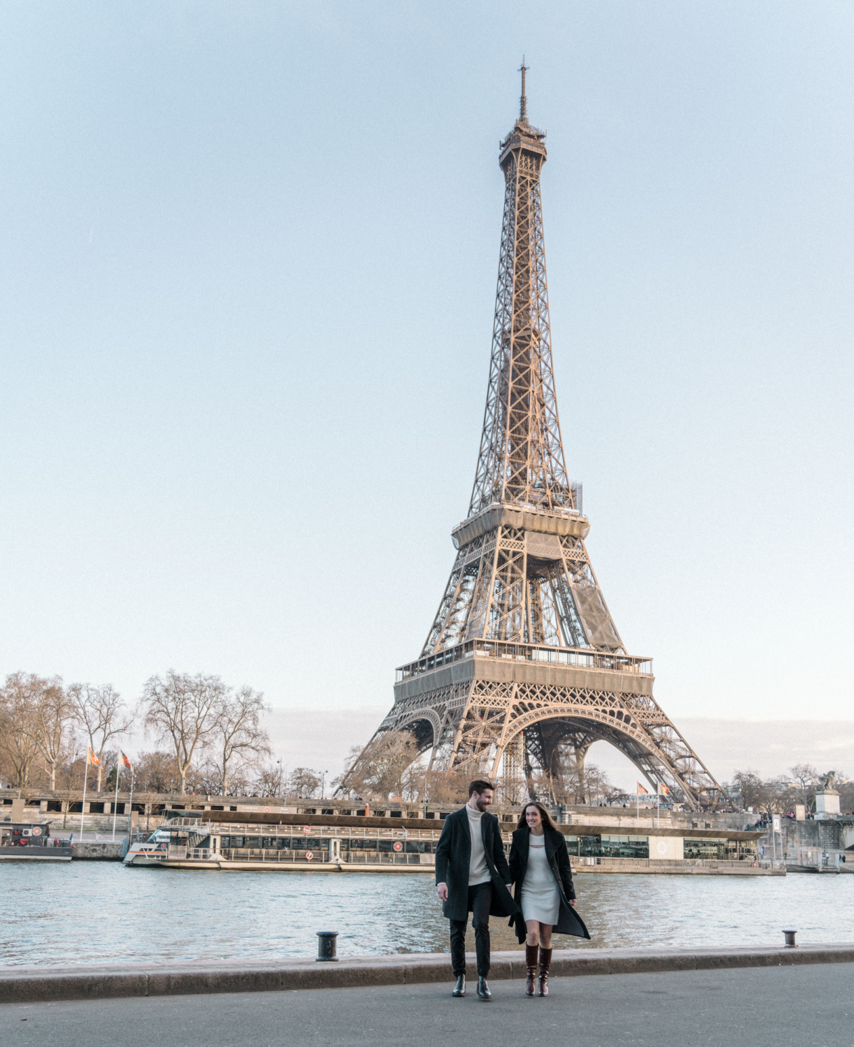 newly engaged couple walk hand in hand with eiffel tower in background
