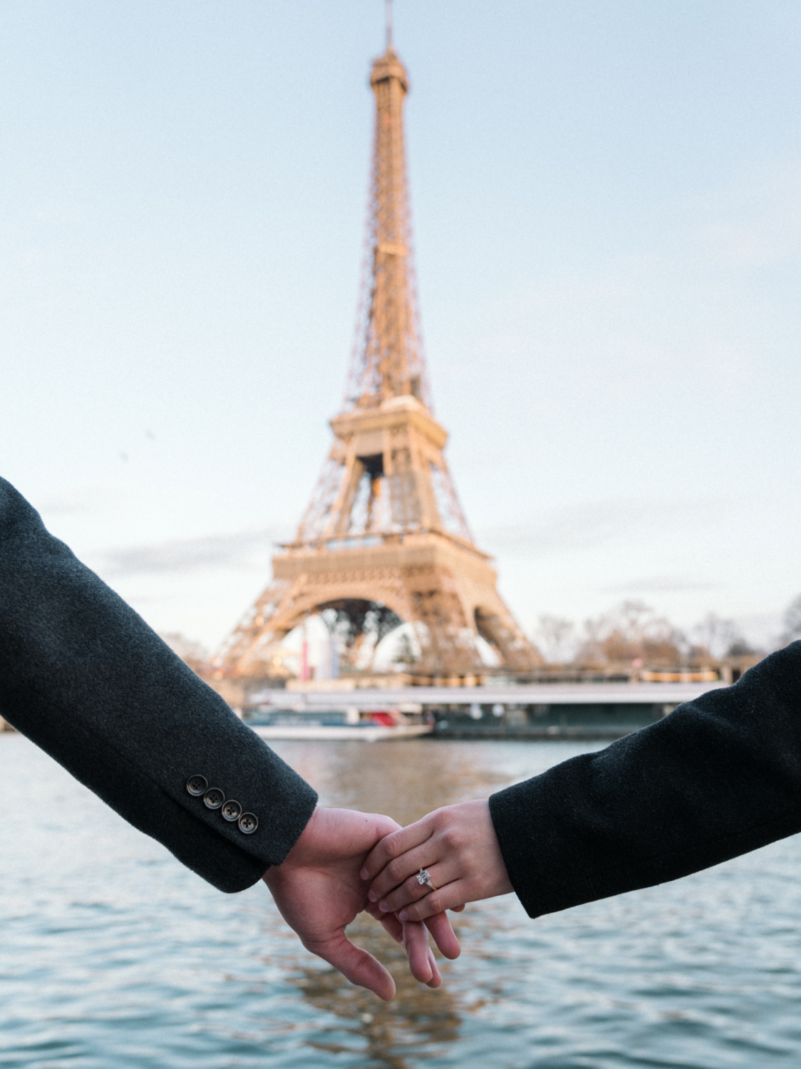 couples holds hands with engagement ring and view of eiffel tower